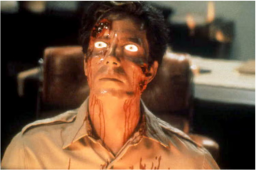 Film still from Scanners showing a seated man with glowing white eyes and blood running down his face.